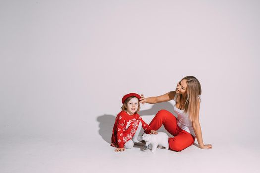 Studio photo of a lovely little girl and beautiful young lady sitting on floor and playing with toy polar bear. Happy Christmas concept