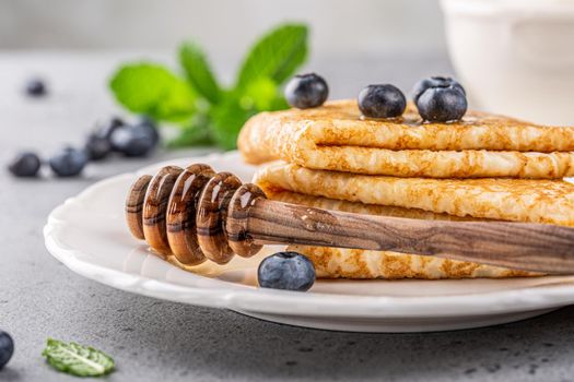 Delicious Tasty Homemade crepes or pancakes with blueberries, honey and mint on white plate. Healthy breakfast concept, gluten free.