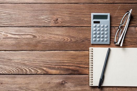 Still life of accountant vintage workspace with office accessories. Flat lay old hardwood desk with notepad, pen and calculator. Business analysis and consulting. Finance and investment concept.