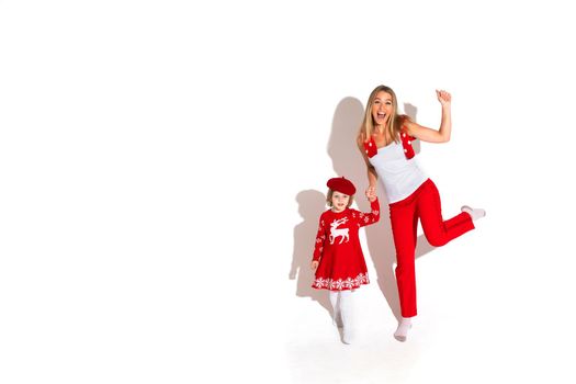 Christmas concept photo of little girl in red dress holding hands with an excited blonde woman while waving at the camera