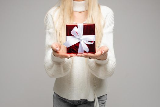 Cropped photo of young woman showing red box while celebrating Christmas, isolated on grey background. New Year holiday concept