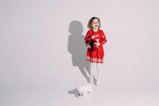 pretty caucasian girl in red dress with a little white bear toy near her