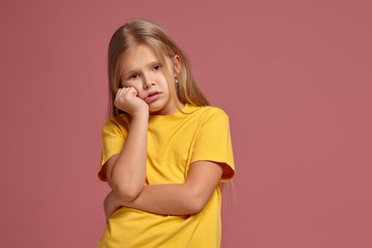 little girl in a yellow T-shirt on a coral background. misses