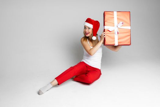 cheerful caucasian woman with red and white hat interests what is inside her gift
