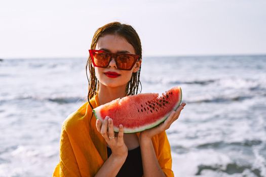 woman on the beach near the ocean eating watermelon. High quality photo
