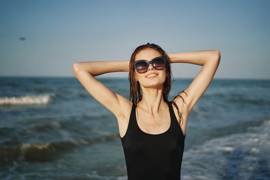 cheerful woman in black swimsuit sunglasses ocean travel. High quality photo