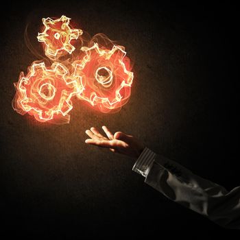 Hand of businessman pointing fire gear mechanism on dark background