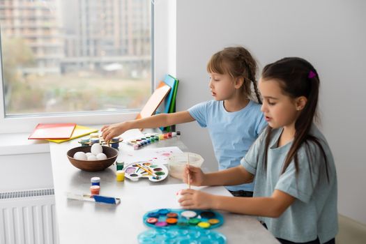 two little girls at the table with paints for drawing