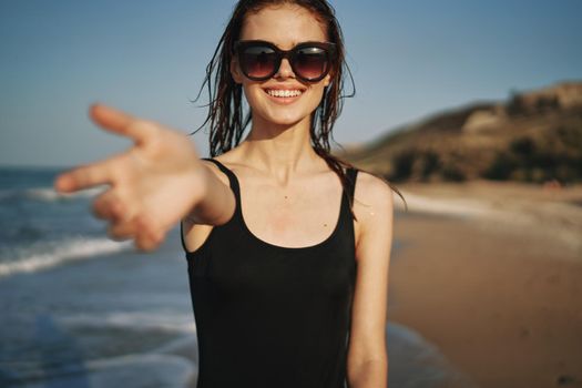 cheerful woman in a black swimsuit walking along the beach tropics summer. High quality photo