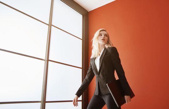 Young adult business woman wearing formalwear and carrying the laptop