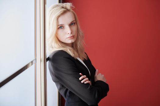 Young adult business woman standing next to the window