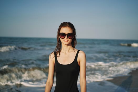 pretty woman in black swimsuit posing sun walking on the beach. High quality photo