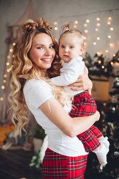 Waist up of happy mother with her cute kid posing at camera on Christmas eve. Holiday concept