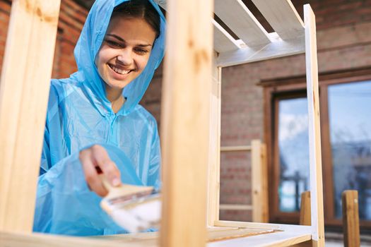 cheerful woman with a paint brush to paint wooden fittings. High quality photo