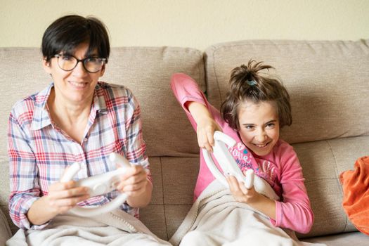 Mother and daughter playing video games at home with a wireless console