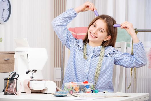 Funny young seamstress playing with colorful coil threads