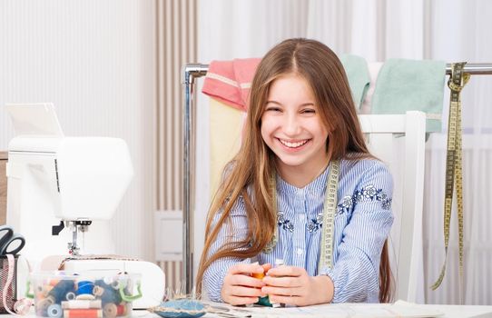 Beatiful teenage girl in popular tailor workshop. holding threads