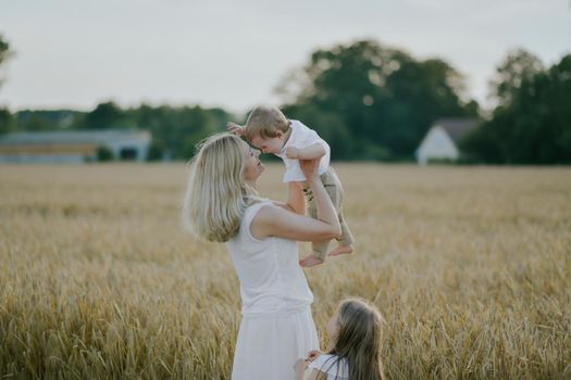 Mother playing with children in a wheat field Countryside