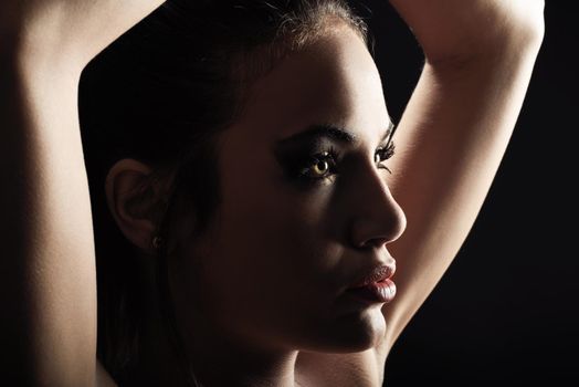 Portrait of beautiful young woman with green eyes on black background