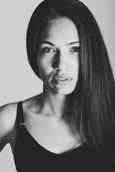 Beautiful young woman without make-up. Beautiful girl with green eyes, model of fashion wearing black tank top on white background.