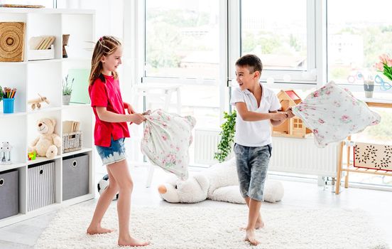 Laughing kids having fun while pillow fight at home