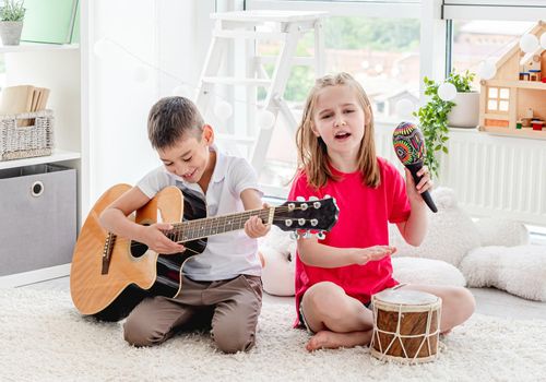 Cute children playing musical instruments in bright room