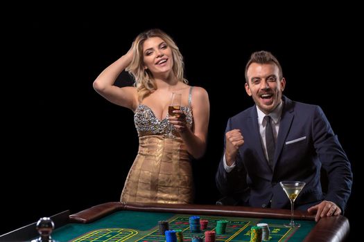 Couple gambling at roulette table in casino. Black background. Excitement. Risk. Luck