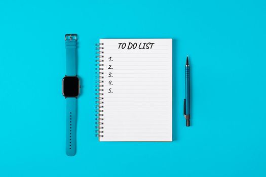 To do list banner. A watch, pencil and modern notebook isolated on blue background from above. Planning and design concept. Top view, flat lay, copy space