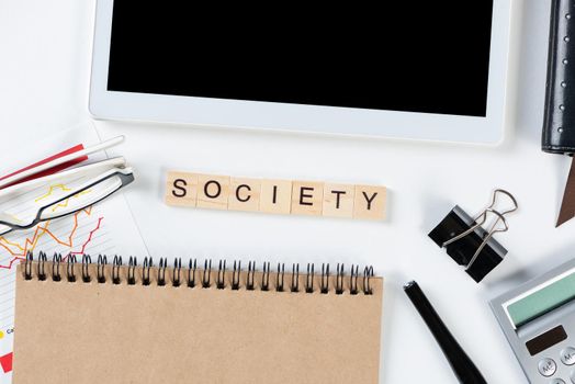 Society people concept with letters on cubes. Still life of workplace with supplies. Flat lay white surface with tablet computer and spiral notebook. Community connection and communication.