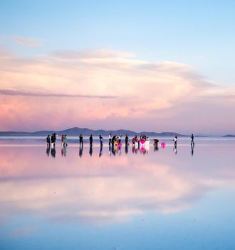 Bolivia - October 21, 2018: Wedding ceremony with fiance and bride walking on the surface of largest mirrored salt flats