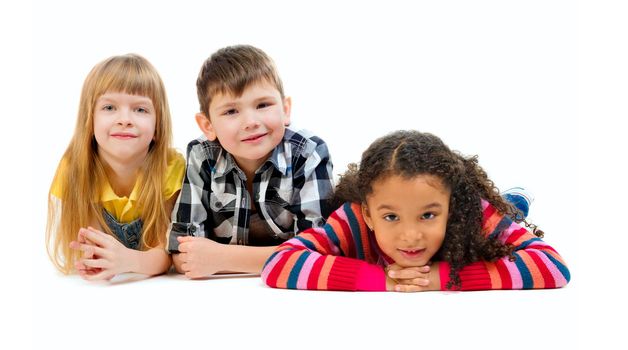 tree cute children lying on the floor in a studio isolated on white background