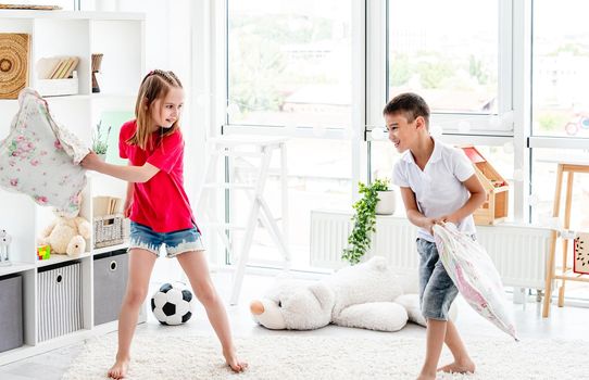 Laughing kids having fun while pillow fight at home