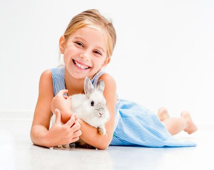 cute smiling girl in a blue dress with a white rabbit
