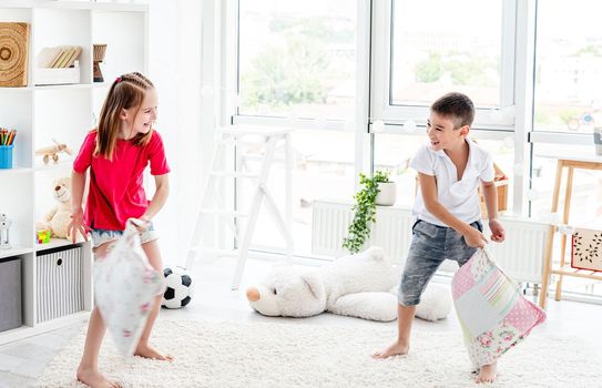 Laughing kids having fun while pillow fight at home