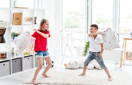 Laughing kids having fun while pillow fight at home