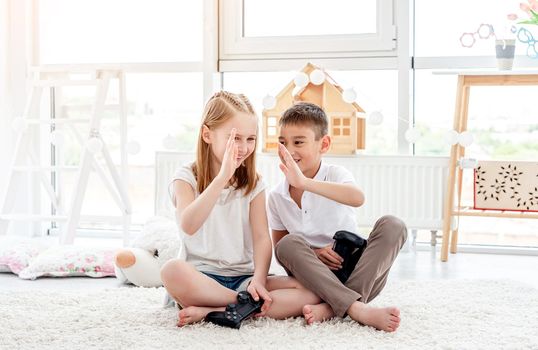 Happy kids giving high five while video gaming in children's room