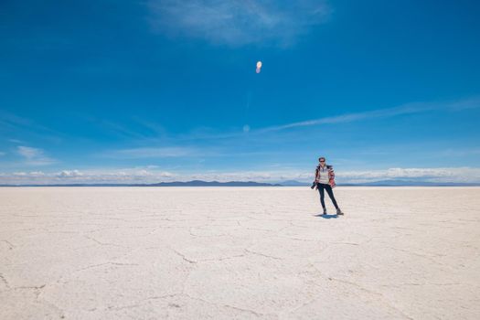 Smiling girl in sunshine wide Salar de Uyuni area in Bolivia