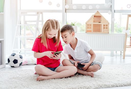 Happy boy and girl children taking selfie on smartphone in kids room