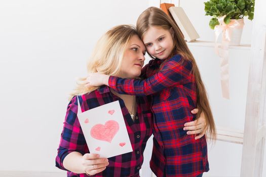 Mother's Day and family holidays - Mother reading greeting card from daughter.