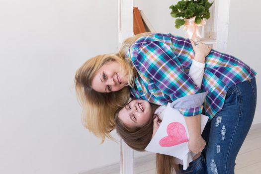 Happy mother's day. Child daughter congratulates mom and gives her postcard. Mum and kid girl smiling and hugging. Family holiday.