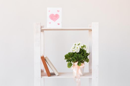 Picture of heart and books and indoor plant on a bookshelf. Minimal composition. Spring interior concept