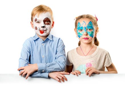 Funny children with creative face art painings with white blank banner for advertising isolated on white background. Copyspace, free space for text