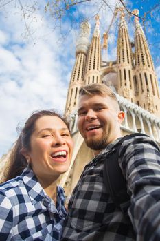 BARCELONA, SPAIN - FEBRUARY 6, 2018: Happy couple making selfie photo in front of the famous Sagrada Familia catholic cathedral. Travel in Barcelona.