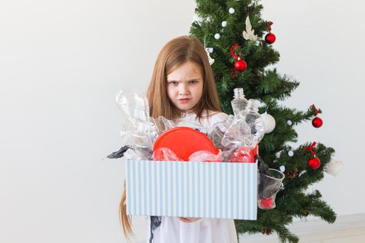 Environmental protection and pollution concept. Surprised child carrier box with plastic trash over christmas tree background