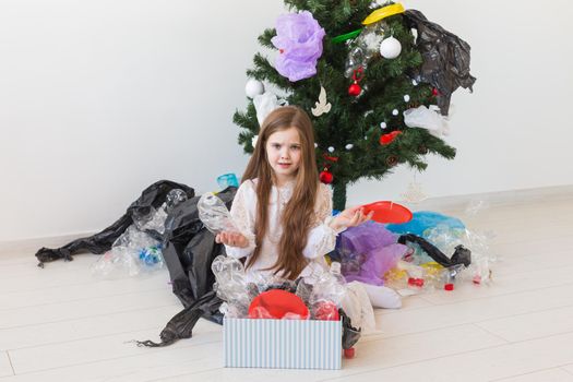 Environmental protection and pollution concept. Surprised child carrier box with plastic trash over christmas tree background