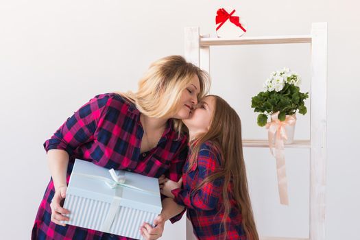 Young mother received a surprise from her daughter feeling excited open the mouth and looking at the gift in amazement in mother's day. Holidays, birthday and presents concept