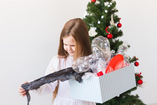 Environmental protection and pollution concept. Surprised child carrier box with plastic trash over christmas tree background