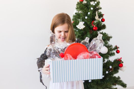 Environmental protection and pollution concept. Surprised child carrier box with plastic trash over christmas tree background