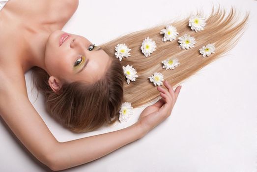attractive young woman lying on white background covered with flowers