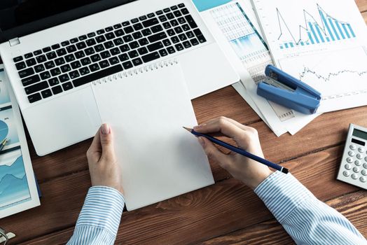 close-up, female hands hold a notebook and pencil. Business woman working at the table in the office